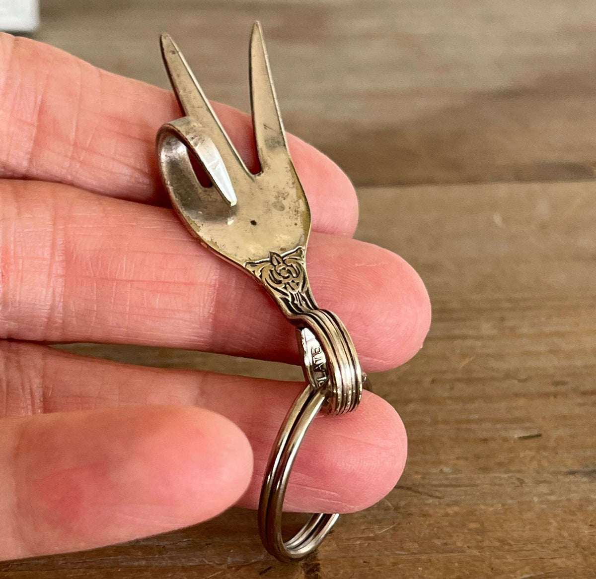Handmade peace sign fork keychain shown in hand for scale - upcycled vintage silverware accessory - Laughing Frog Studio