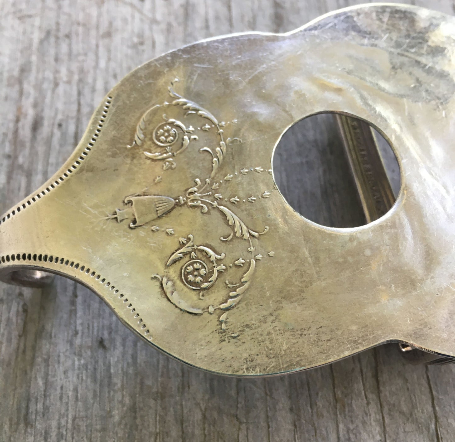 Close-up detail of guitar belt buckle showing drilled sound hole and decorative bowl pattern on upcycled vintage casserole spoon, 4.5 x 2.625 inches