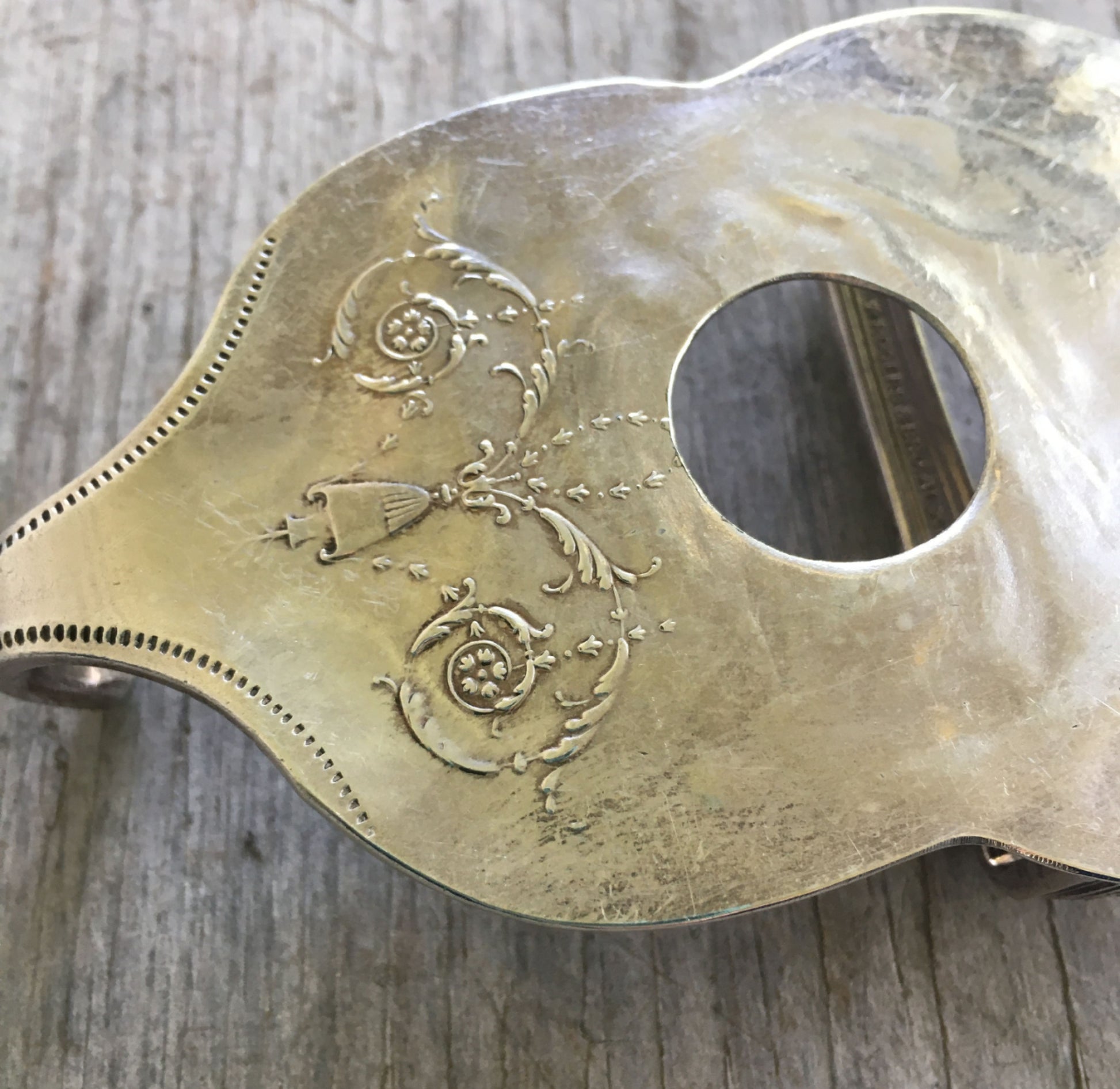 Close-up detail of guitar belt buckle showing drilled sound hole and decorative bowl pattern on upcycled vintage casserole spoon, 4.5 x 2.625 inches