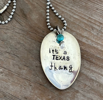 Close-up of IT'S A TEXAS THANG hand-stamped spoon pendant with decorative beads showing Texas pride message on reclaimed vintage silverware, 18-inch chain, one-of-a-kind