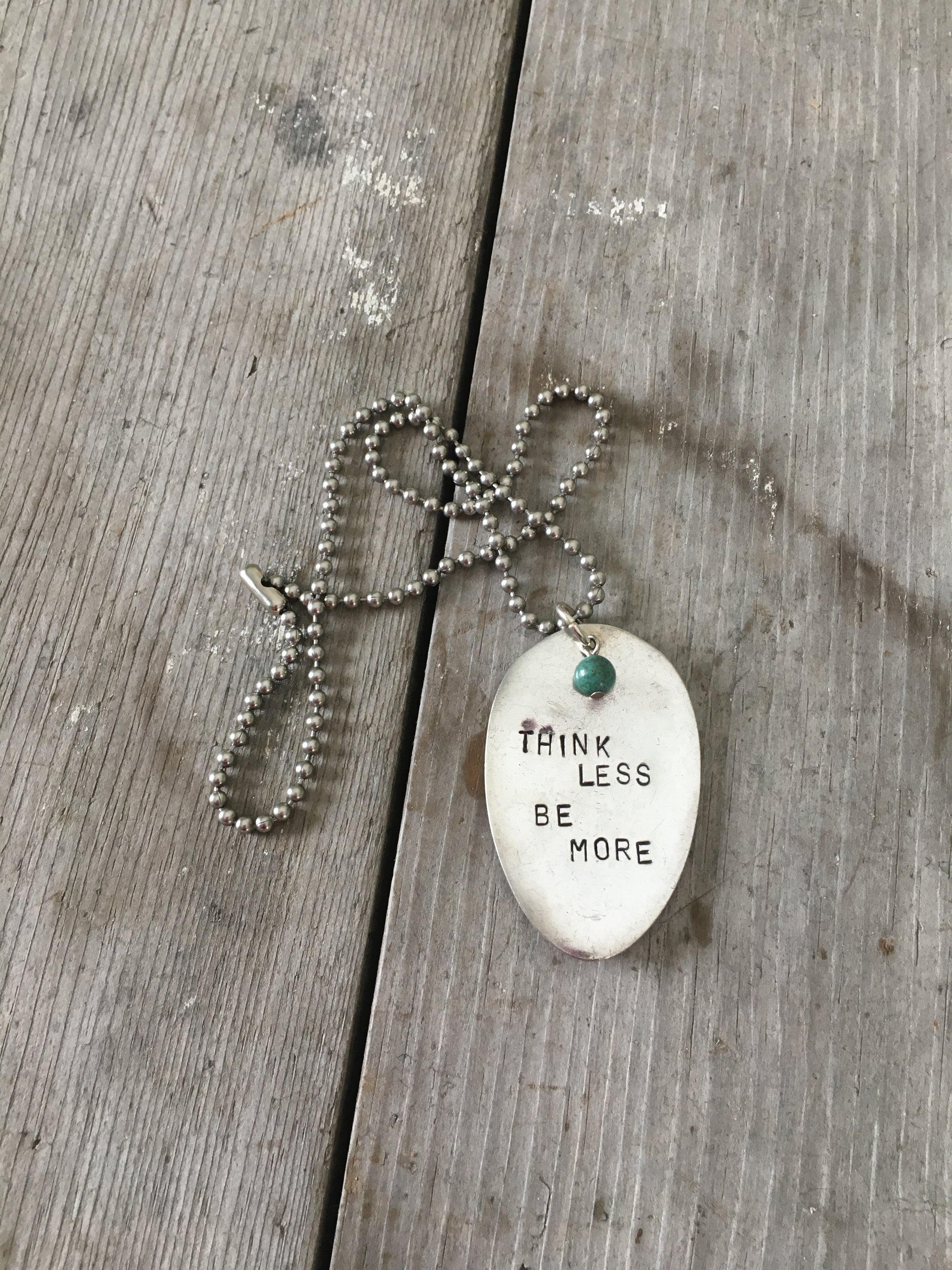 THINK LESS BE MORE stamped spoon necklace showing hand-stamped lettering and turquoise sphere bead detail, 18-inch chain, one-of-a-kind