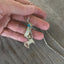 Spoon Artisan Necklace in the shape of a Quarter Rest and Eighth Note Musical Symbols Shown in hand for scale