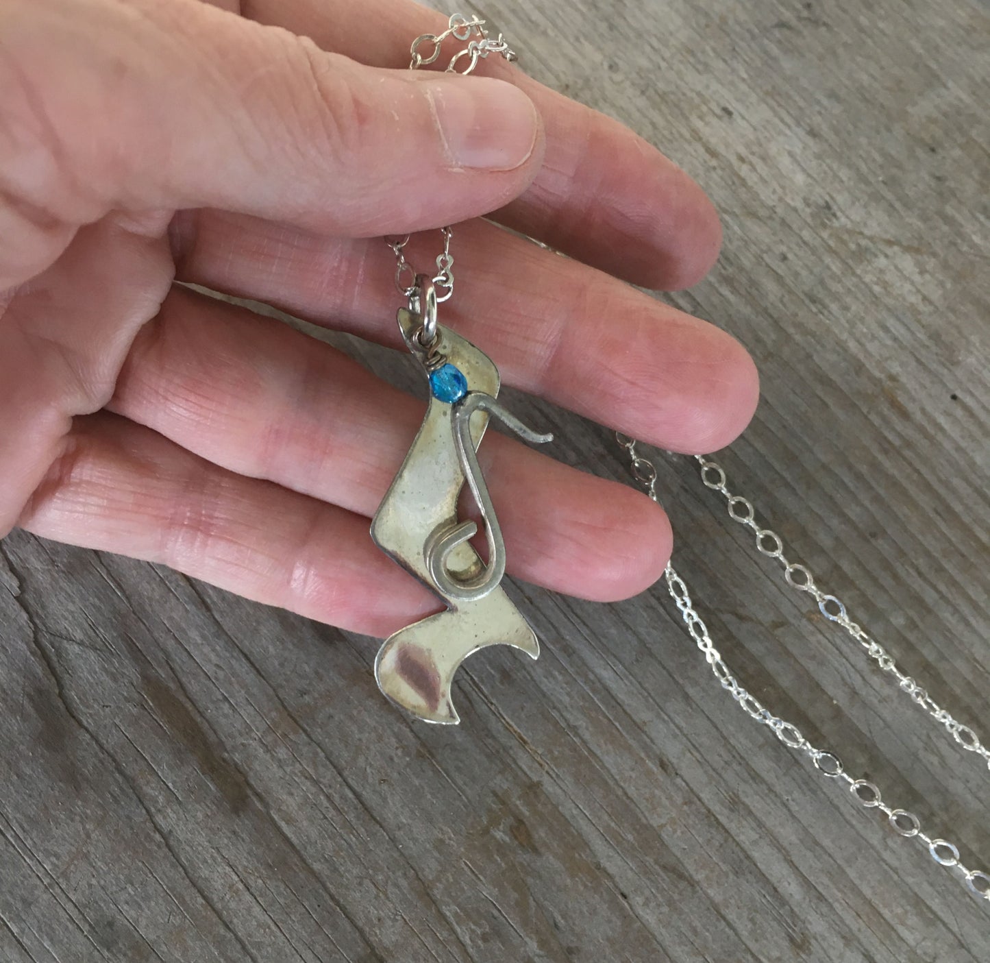 Spoon Artisan Necklace in the shape of a Quarter Rest and Eighth Note Musical Symbols Shown in hand for scale