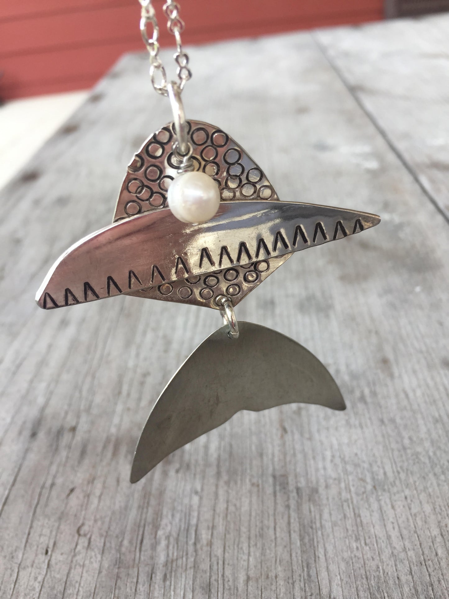 Close-up detail of articulated fish pendant made from upcycled vintage spoons with cultured pearl - handcrafted artisan necklace