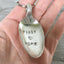 Spoon keychain hand stamped with FIRST HOME and a heart shown in hand for size and scale