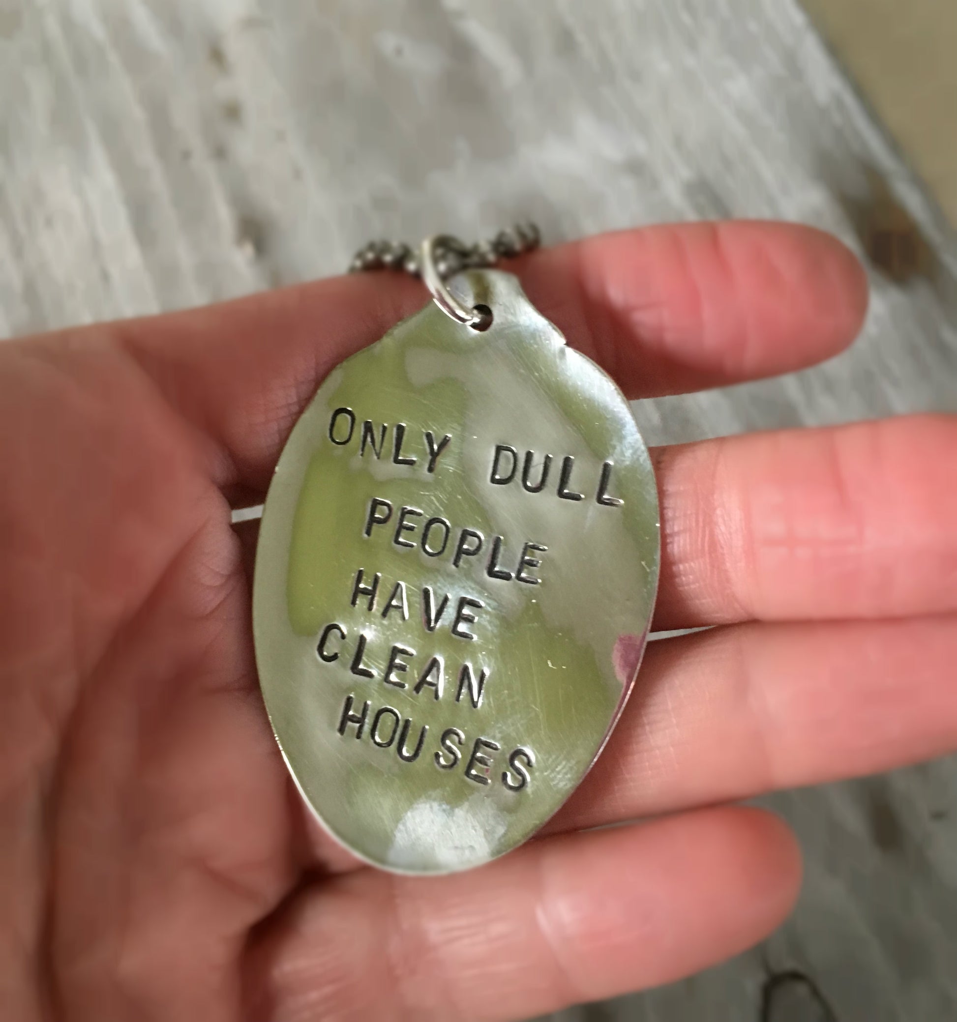 close up view of stamping on ONLY DULL PEOPLE HAVE CLEAN HOUSES stamped spoon necklace showing hand-stamped lettering, layerable gypsy style fun housekeeping humor jewelry, one-of-a-kind
