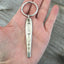 Silverware handle keychain stamped HOME shown in hand for sca;e