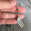 Close-up detail of cocktail fork tine earring with lavender Czech glass bead and trident prong design