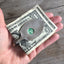 Handmade money clip shown in hand for scale shaped like a guitar or ukele