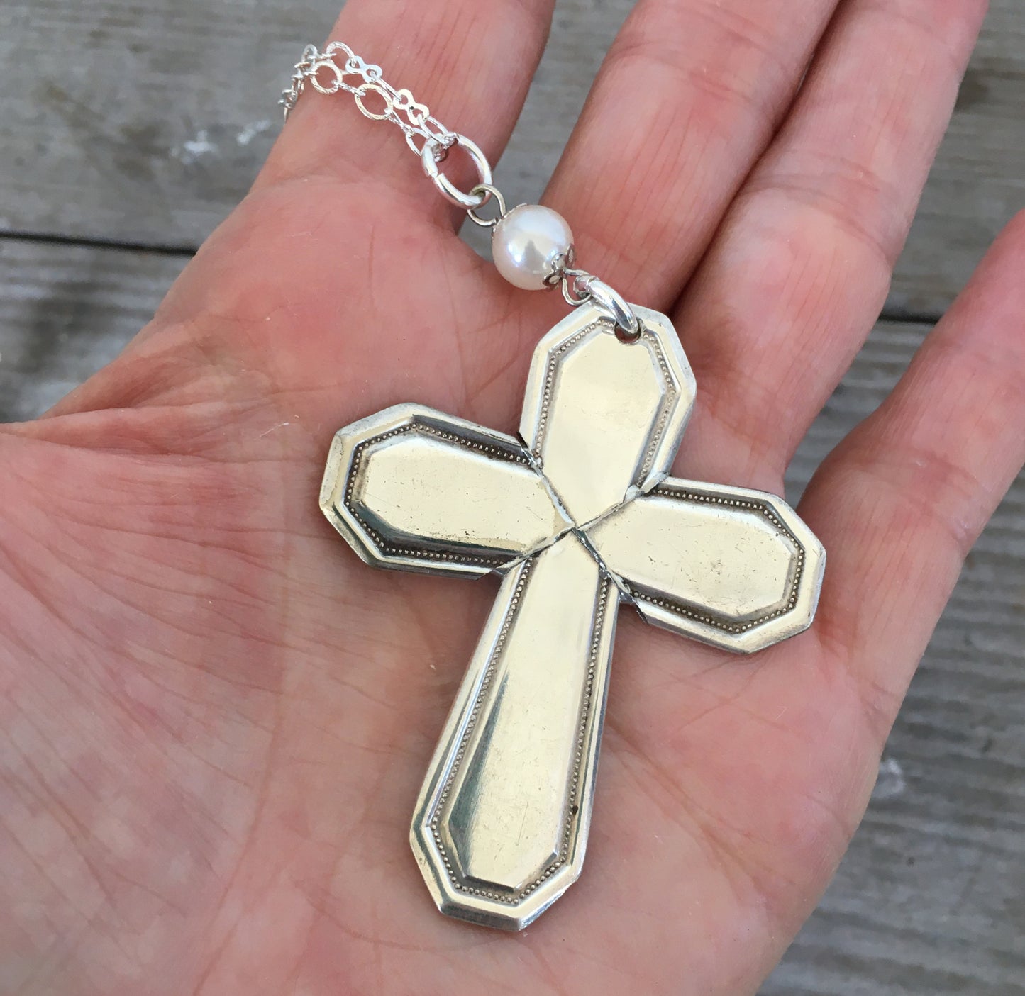 Vintage 1923 William Rogers Mayfair spoon handles transformed into artisan cross pendant shown in hand for scale
