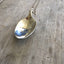 Close-up of DREAM hand-stamped spoon pendant with pickup truck showing inspirational message on reclaimed vintage silverware, 18-inch chain