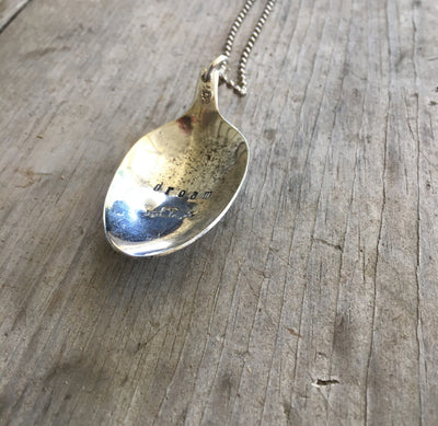 Close-up of DREAM hand-stamped spoon pendant with pickup truck showing inspirational message on reclaimed vintage silverware, 18-inch chain
