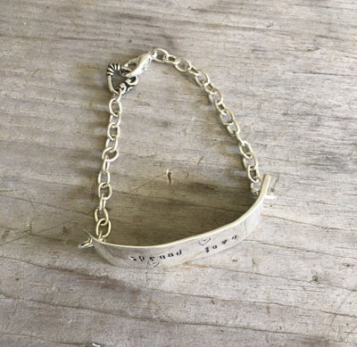Close-up of Spread Love hand-stamped message on vintage knife bracelet - eco-friendly upcycled silverware artisan jewelry