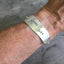 Spread Love stamped knife bracelet with heart charm modeled on wrist - handcrafted upcycled vintage silverware jewelry