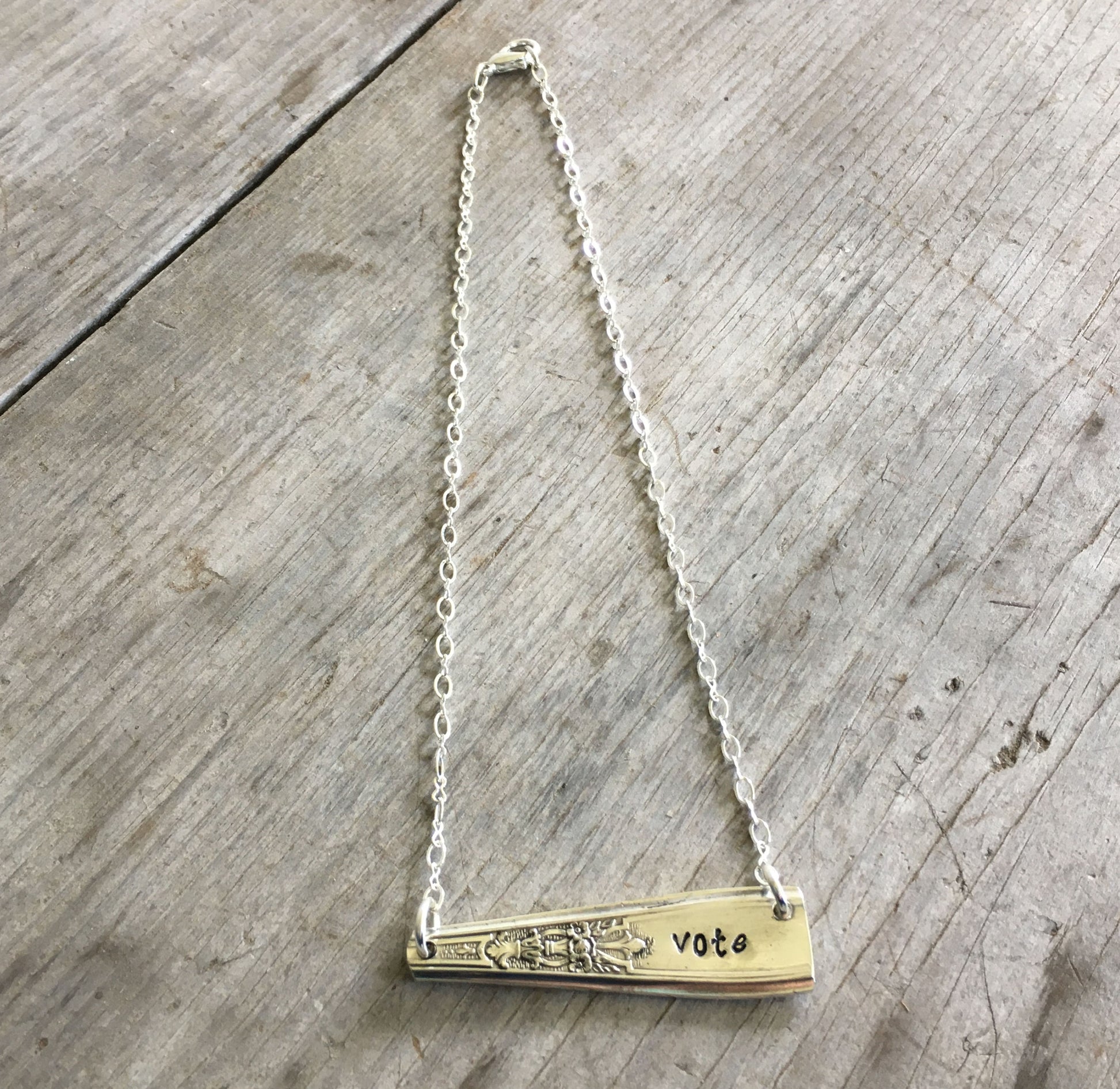 Close-up detail of VOTE bar pendant showing hand-stamped lettering on vintage Ambassador pattern silverware, 2.125 inches wide