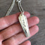 Close-up detail of VOTE bar pendant showing hand-stamped lettering and classic engraved urn with foliage, minimalist heirloom design, 21-inch chain
