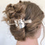 A close-up image of a half-moon shaped hair stick barrette with a vintage cake server design, featuring a silver-colored punched pattern.