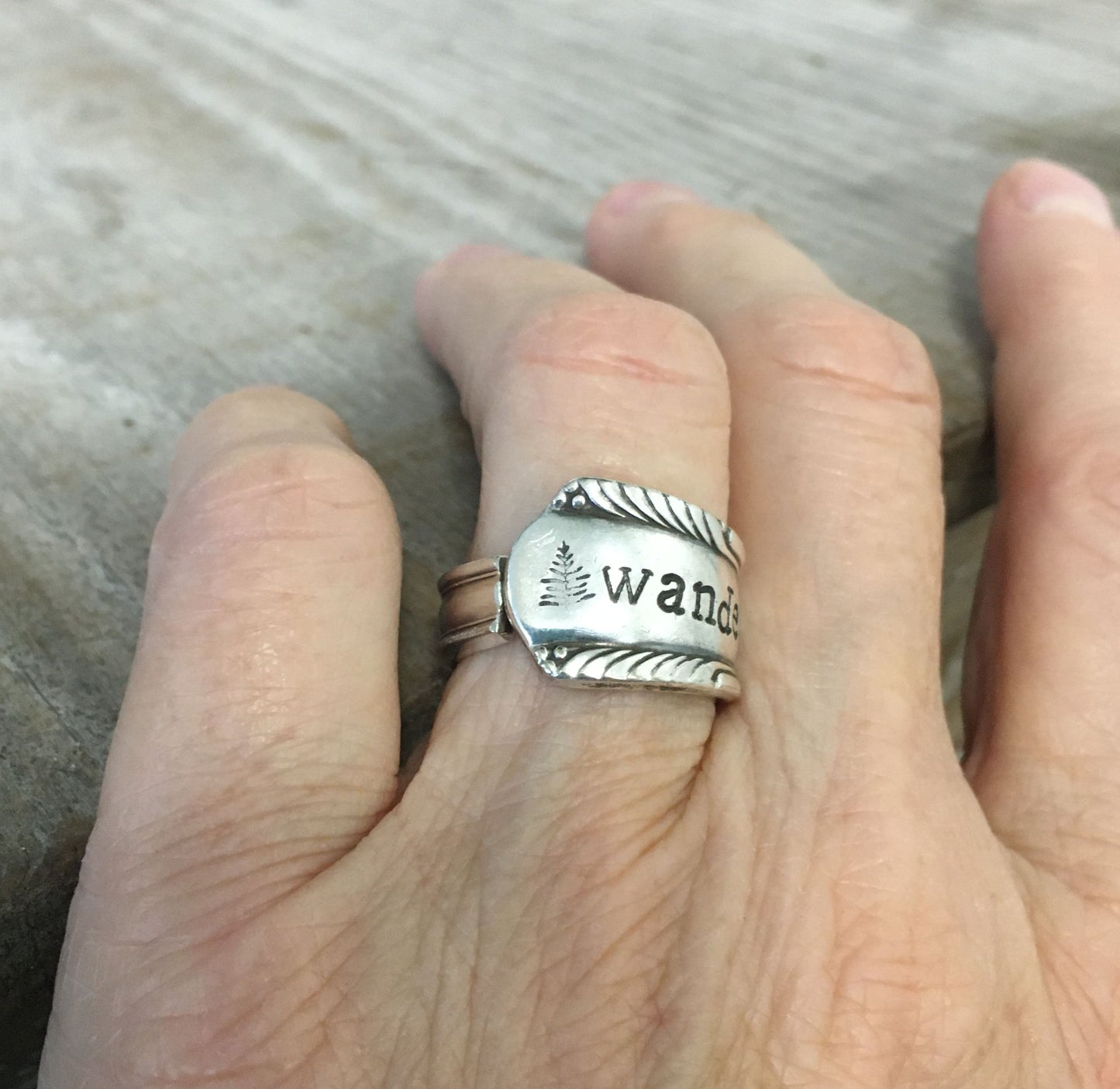 Hand stamped WANDER spoon ring worn on finger displaying size and fit of upcycled silverware ring
