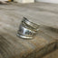 Close-up of hand-stamped mountains scene and WANDER inscription on vintage spoon ring