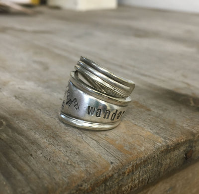 Close-up of hand-stamped mountains scene and WANDER inscription on vintage spoon ring