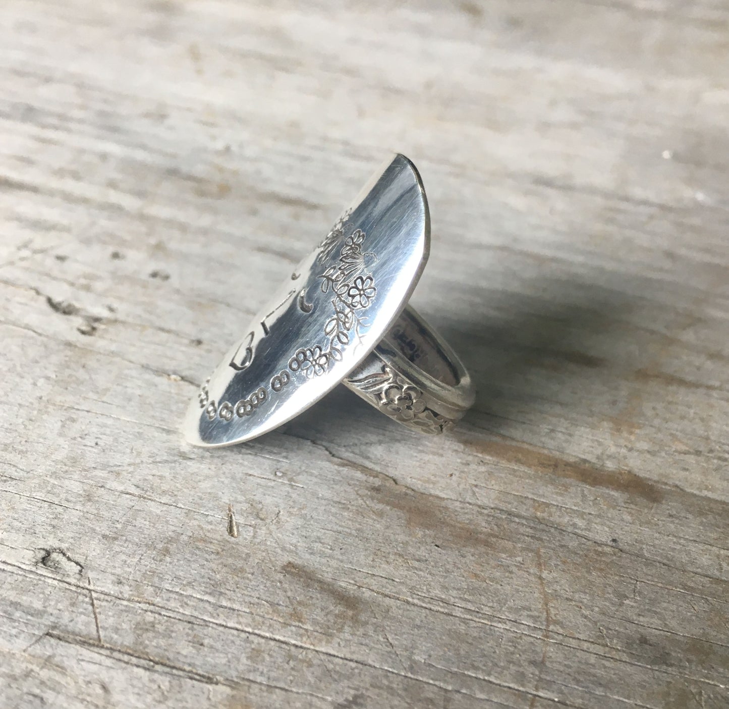 Side view of Women of Nature Sage spoon ring showing hand-stamped woman's face and flower shank detail