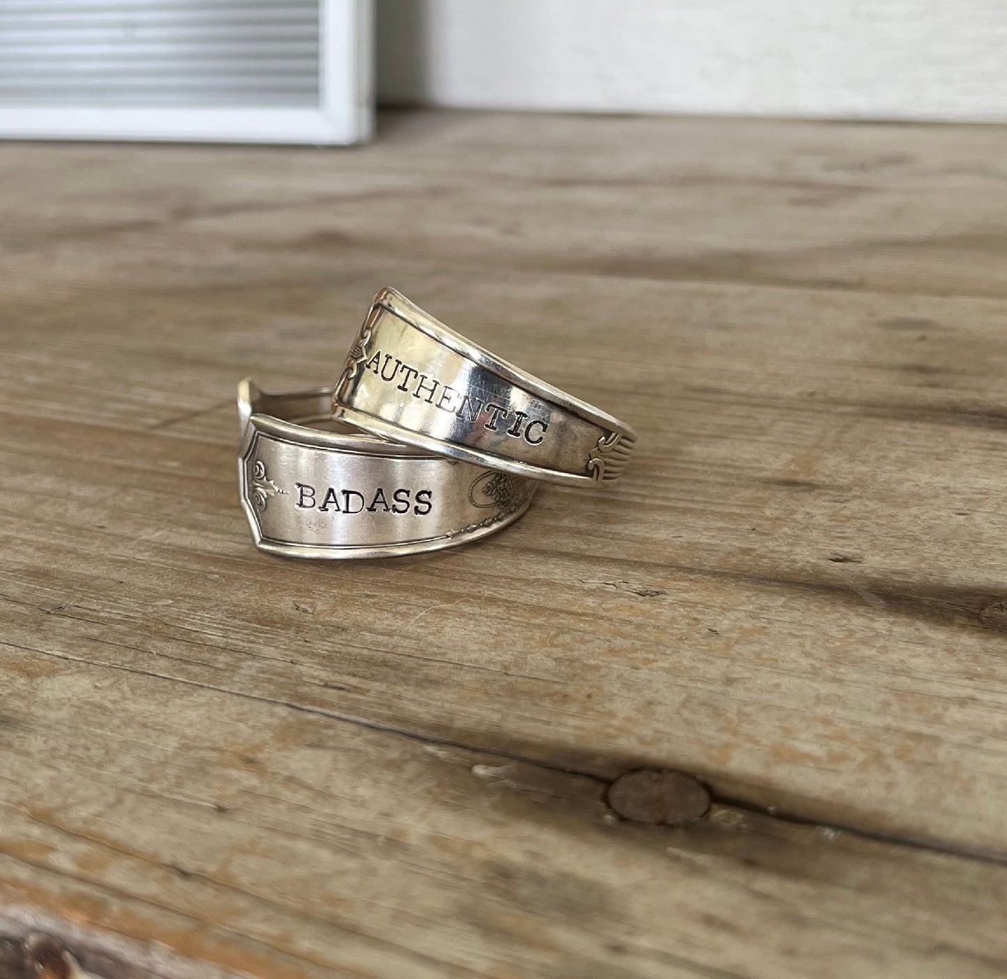 Pair of handstamped upcycled spoon cuff bracelets stamped with BADASS and AUTHENTIC