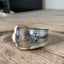 Close-up detail of WANDER hand-stamped spoon cuff bracelet showing mountain and evergreen design with vintage hotel silverplate