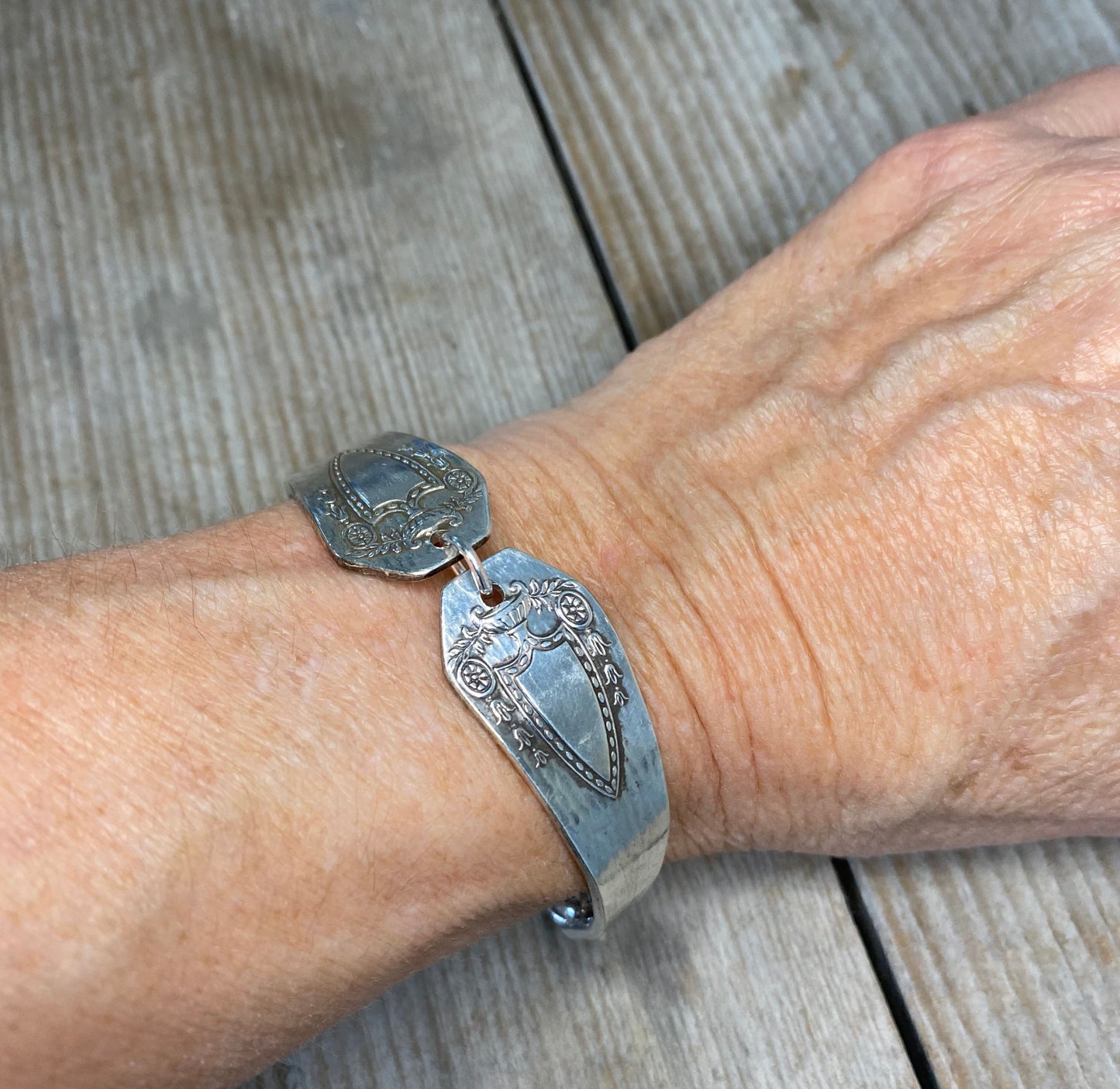 Heraldic spoon link bracelet modeled on wrist - handcrafted upcycled vintage silverware jewelry