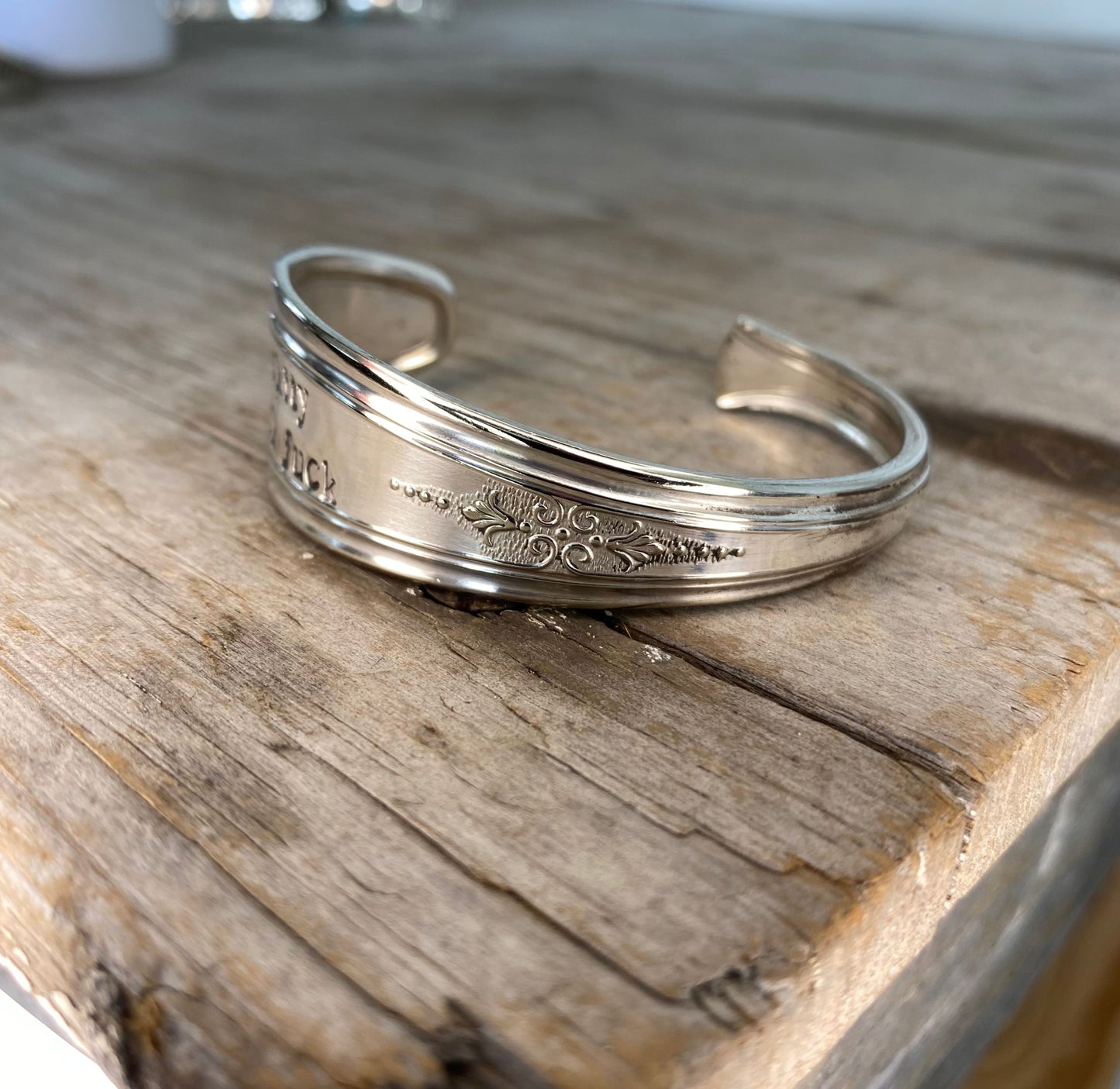 Top view of Upcycled silverware spoon cuff bracelet with hand stamped words FUCKITY FUCK FUCK