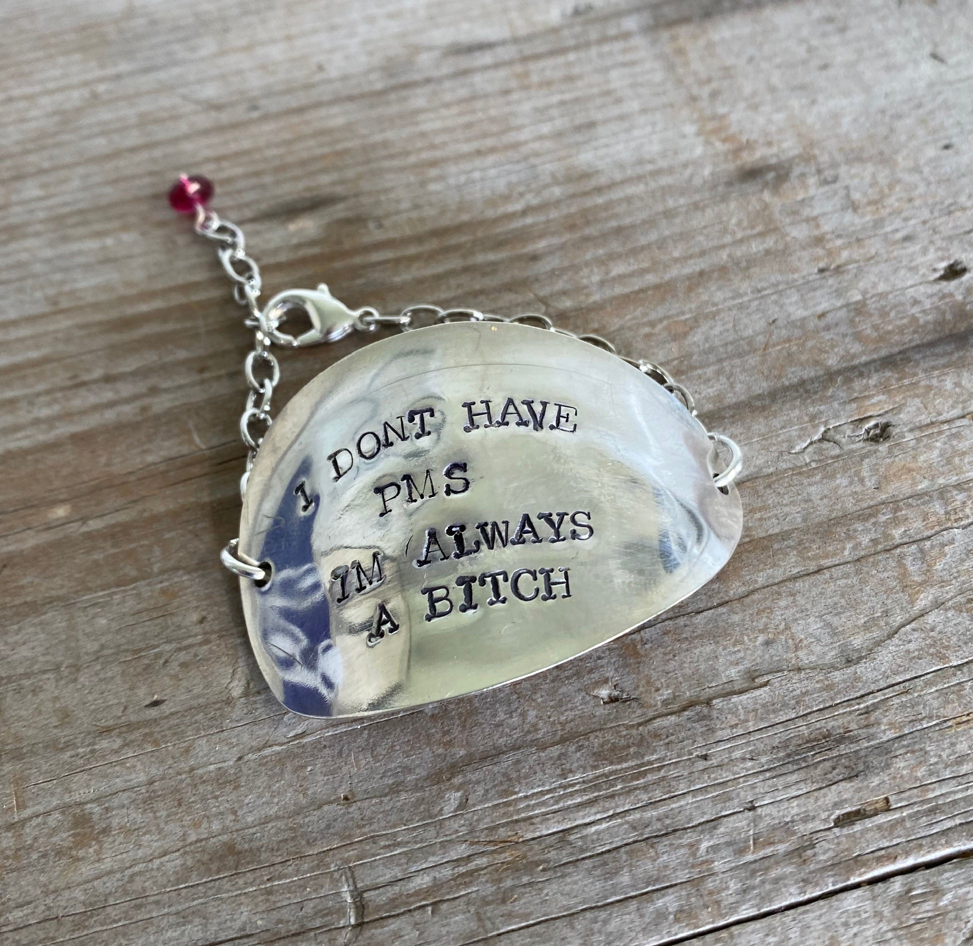 Hand-stamped vintage spoon bracelet with 'I Don't Have PMS I'm Always A Bitch' message and deep magenta glass bead accent