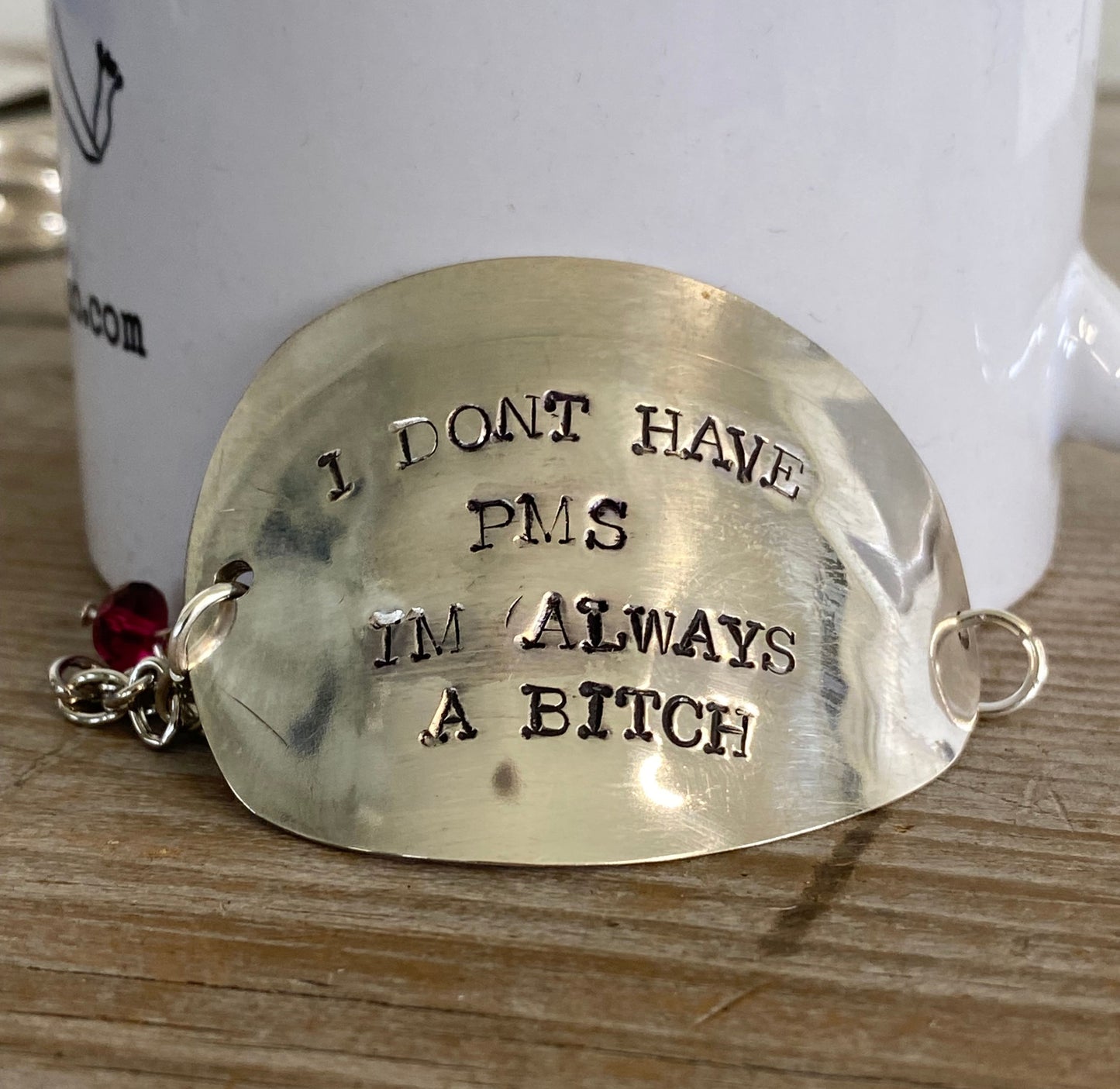 Close-up of hand-stamped lettering and magenta bead detail on flattened vintage spoon bowl bracelet