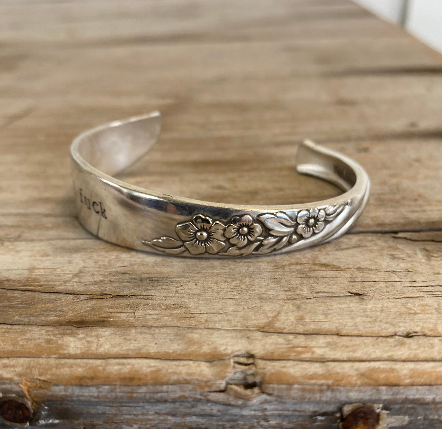 Top view of flowers on Upcycled silverware spoon cuff bracelet with handstamped words FUCKITY FUCK FUCK