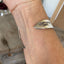 Upcycled silverware mermaid cuff bracelet worn on wrist, showing hand-carved fin, hand stamping and adjustable fit