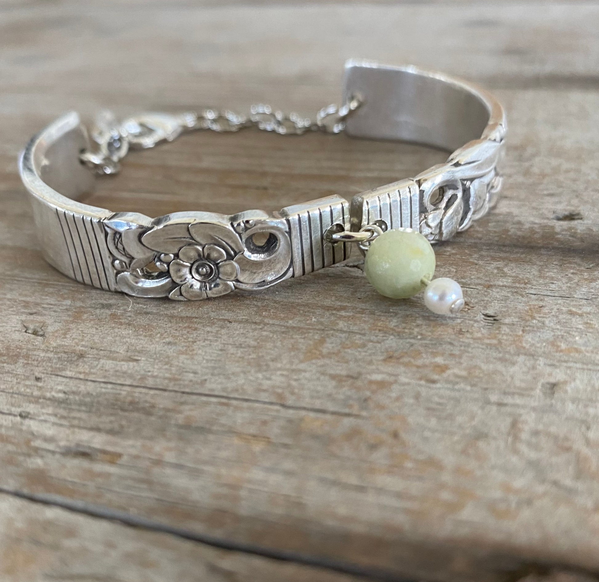 Close up view of upcycled silverware jewelry spoon link bracelet with Peridot stone bead