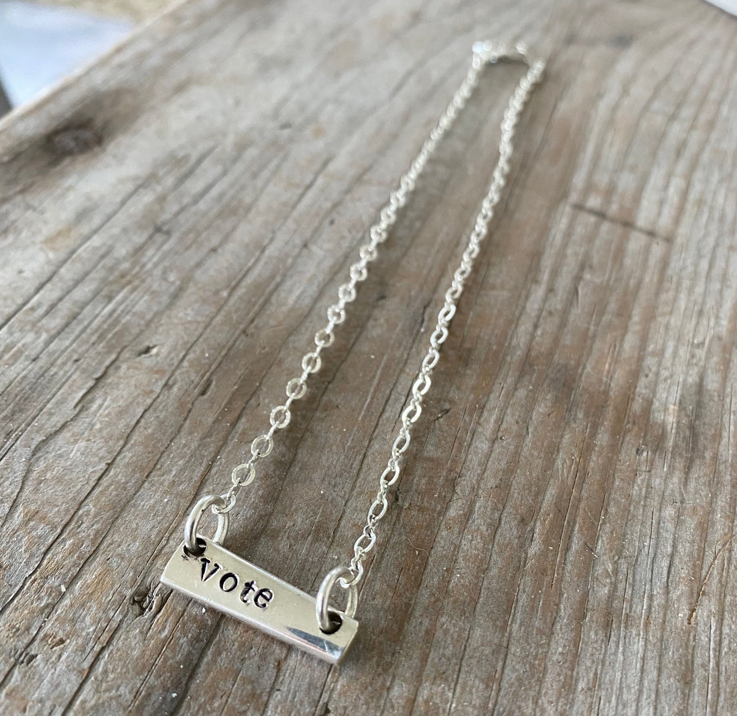 Close-up detail of VOTE bar choker showing hand-stamped lettering on vintage silverware, sits at collarbone, 6.5-inch drop