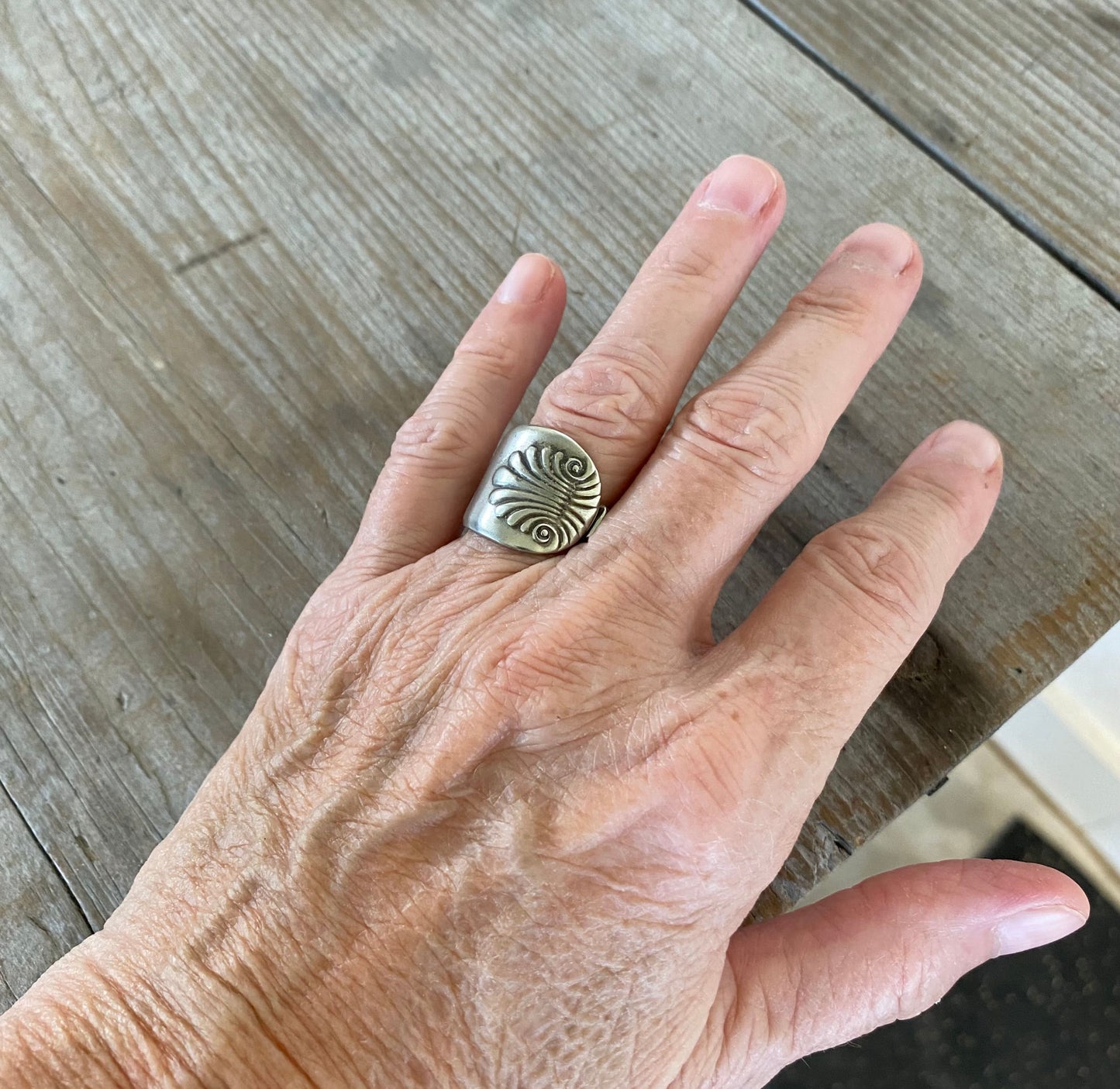 Shell spoon ring worn on finger displaying size and fit of upcycled silverware ring