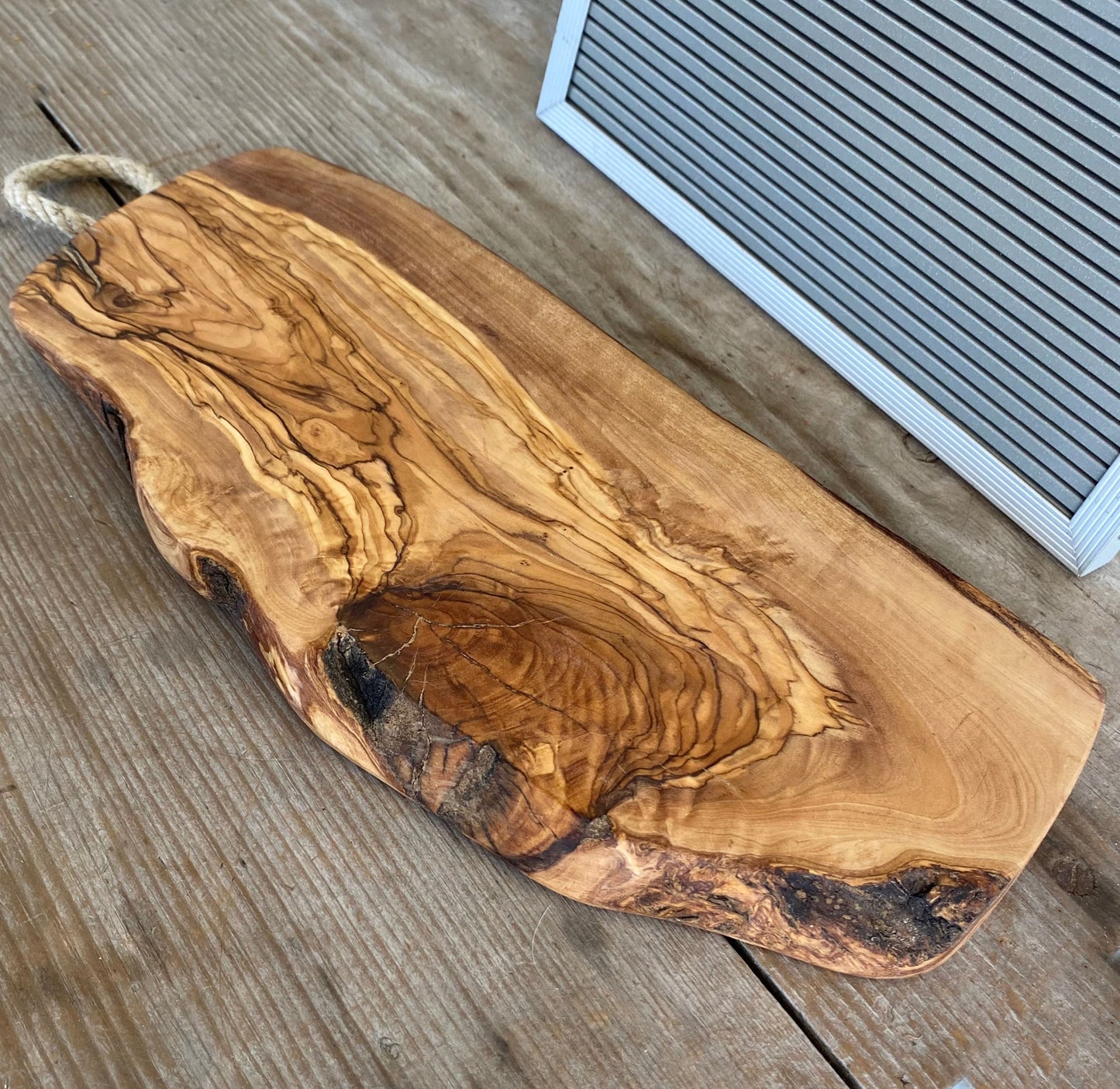 Italian olivewood charcuterie board with rustic bark edge and rope handle - handcrafted from 150-year-old wood