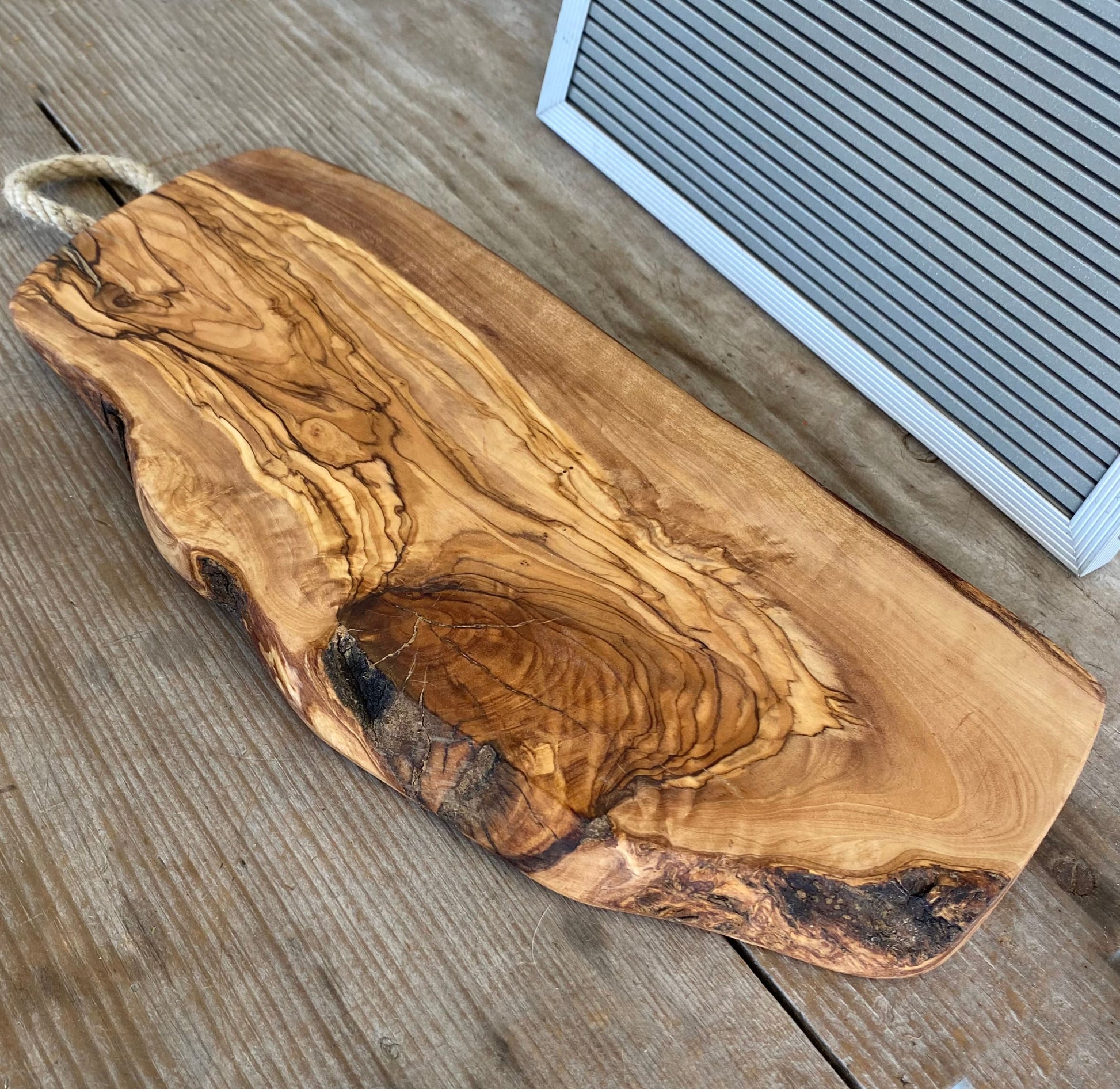 Italian olivewood charcuterie board with rustic bark edge and rope handle - handcrafted from 150-year-old wood