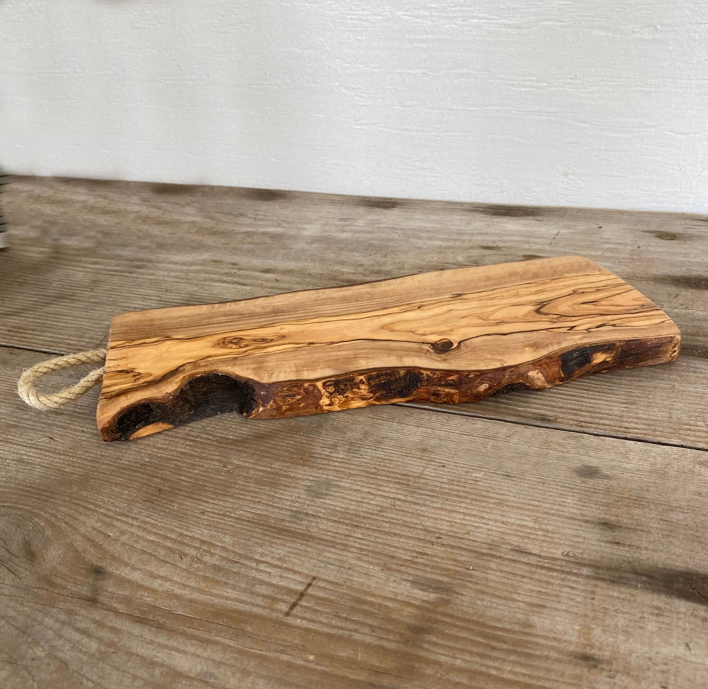 Italian olivewood charcuterie board with rustic bark edge and rope handle - handcrafted from 150-year-old wood