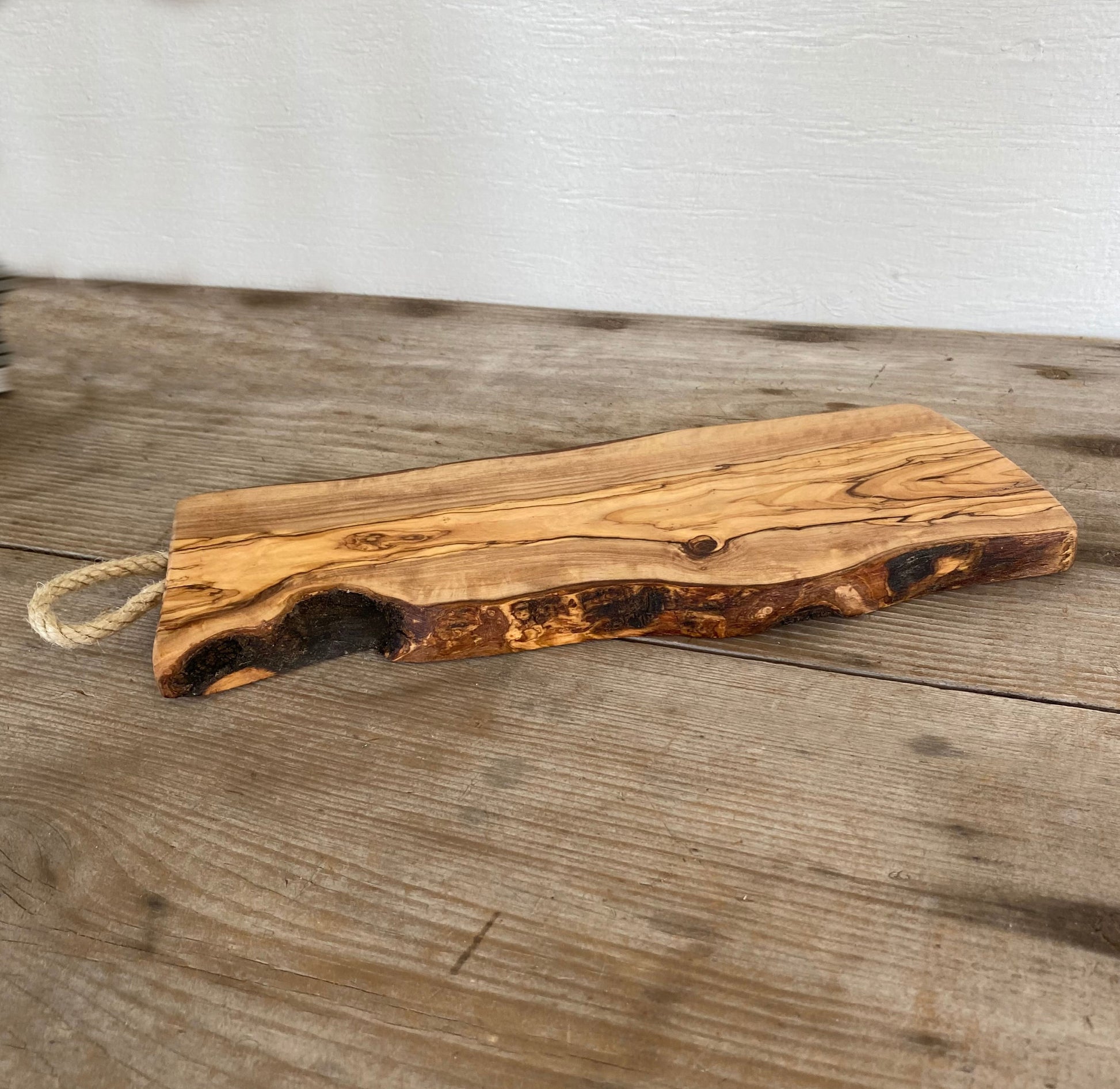 Italian olivewood charcuterie board with rustic bark edge and rope handle - handcrafted from 150-year-old wood