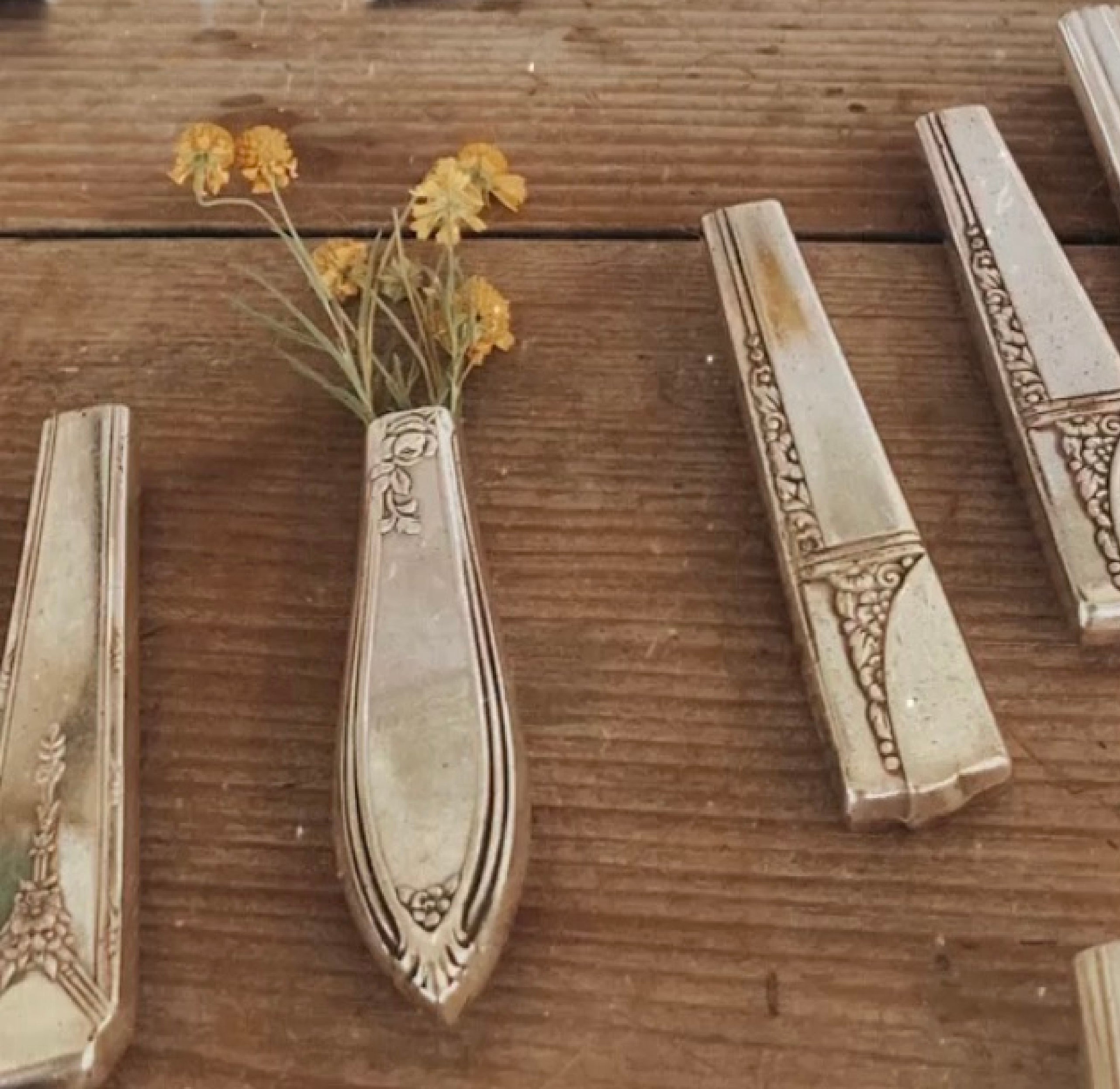 Upcycled vintage Rosemary pattern silverplate knife vase with magnet holding wildflowers on wooden surface