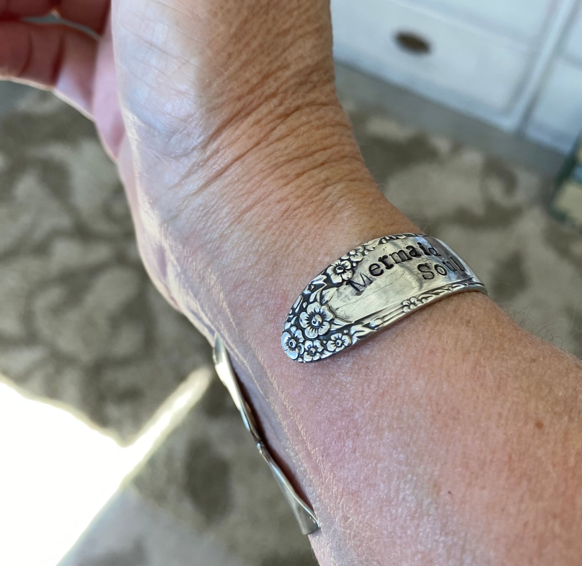 Close-up of hand-stamped Mermaid Soul lettering and carved mermaid tail fin on vintage English Garden spoon cuff