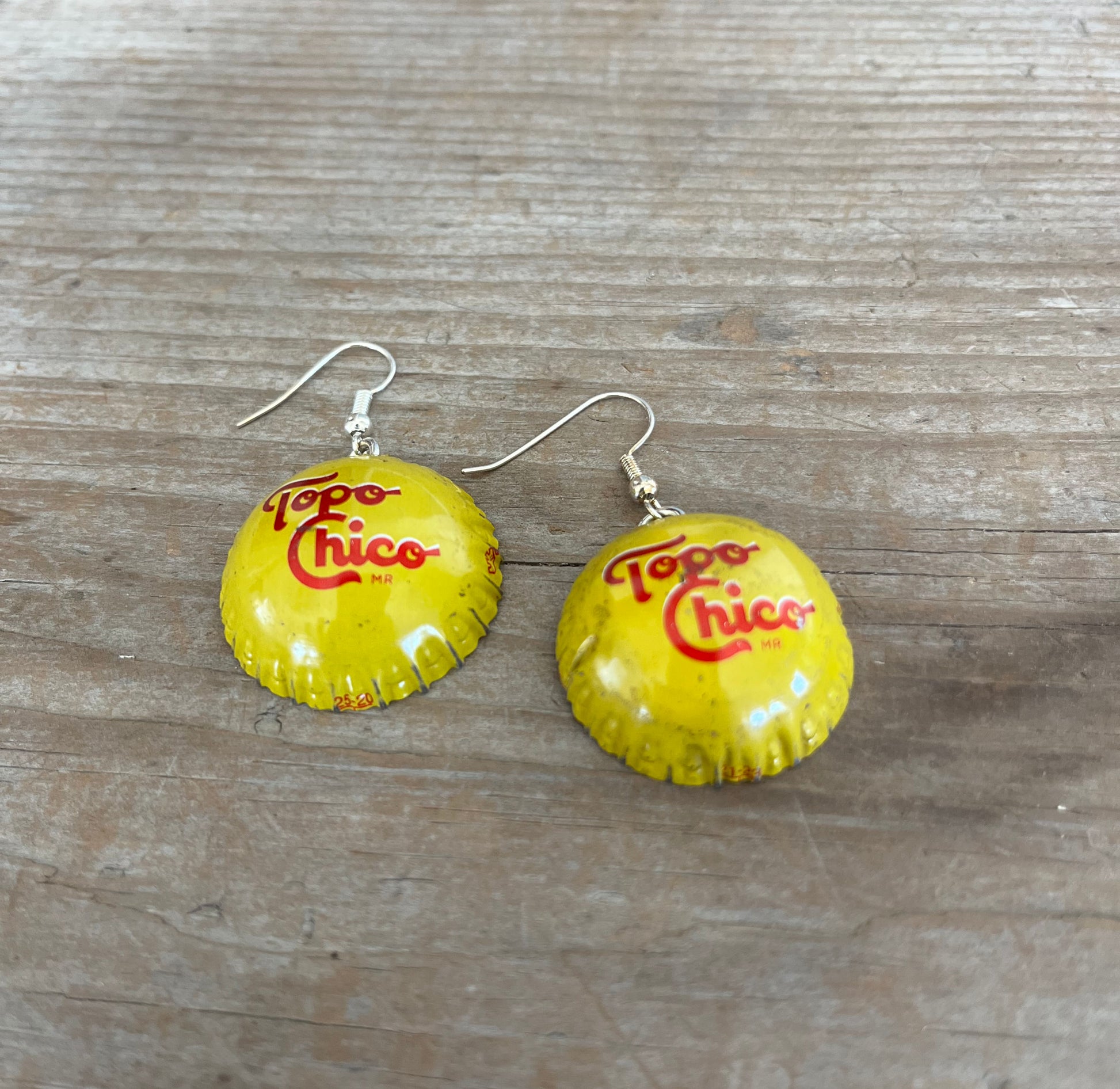 Close-up detail of Topo Chico bottle cap earrings showing smooth reshaped design and playful fizzy energy, 1.875 inches long