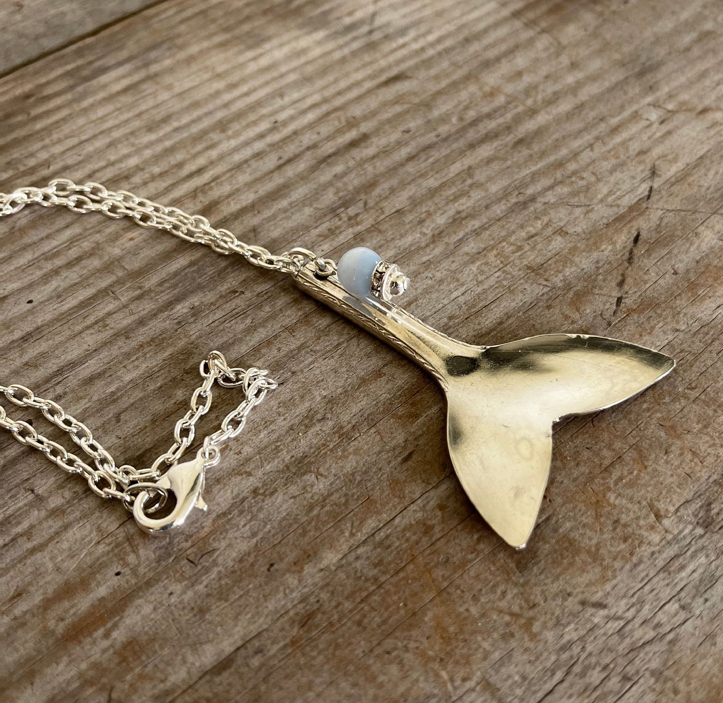Side view of upcycled spoon mermaid tail necklace with rhinestone sparkle bead on 20-inch silverplate chain, one-of-a-kind jewelry