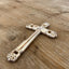 vintage silverware cross Bible page weight resting on open book showing floral detail