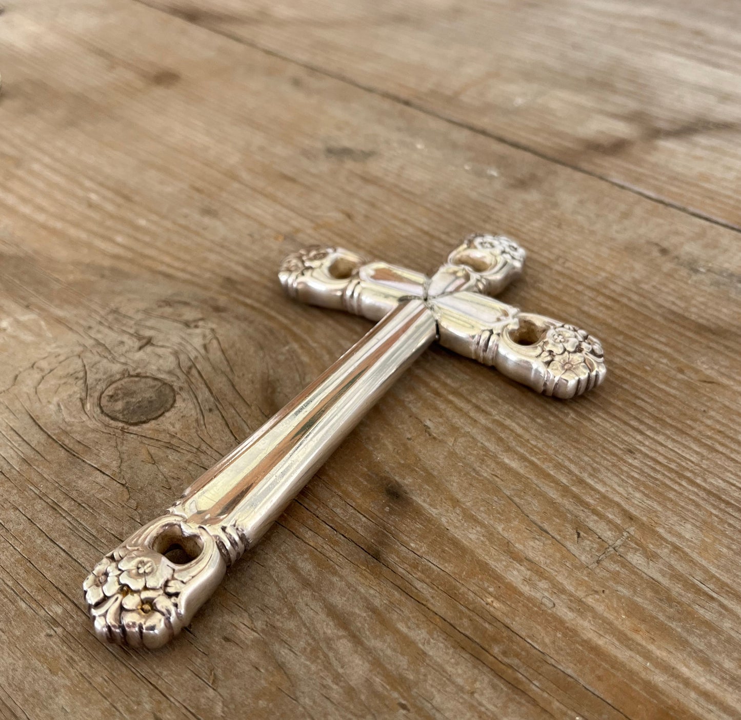 vintage silverware cross Bible page weight resting on open book showing floral detail