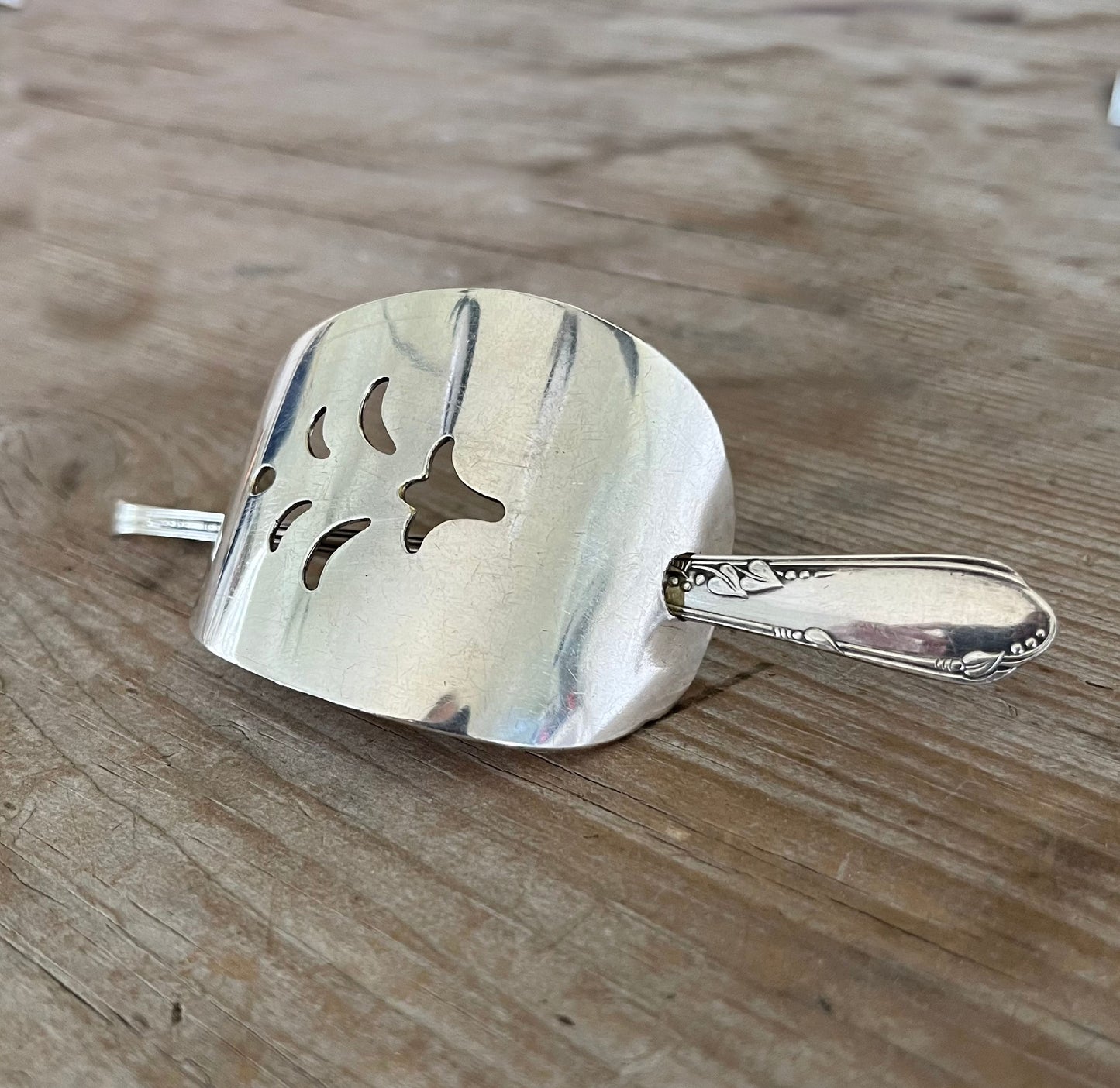 Close-up of vintage cake server barrette showing elegant pierced cutouts and spoon stick detail