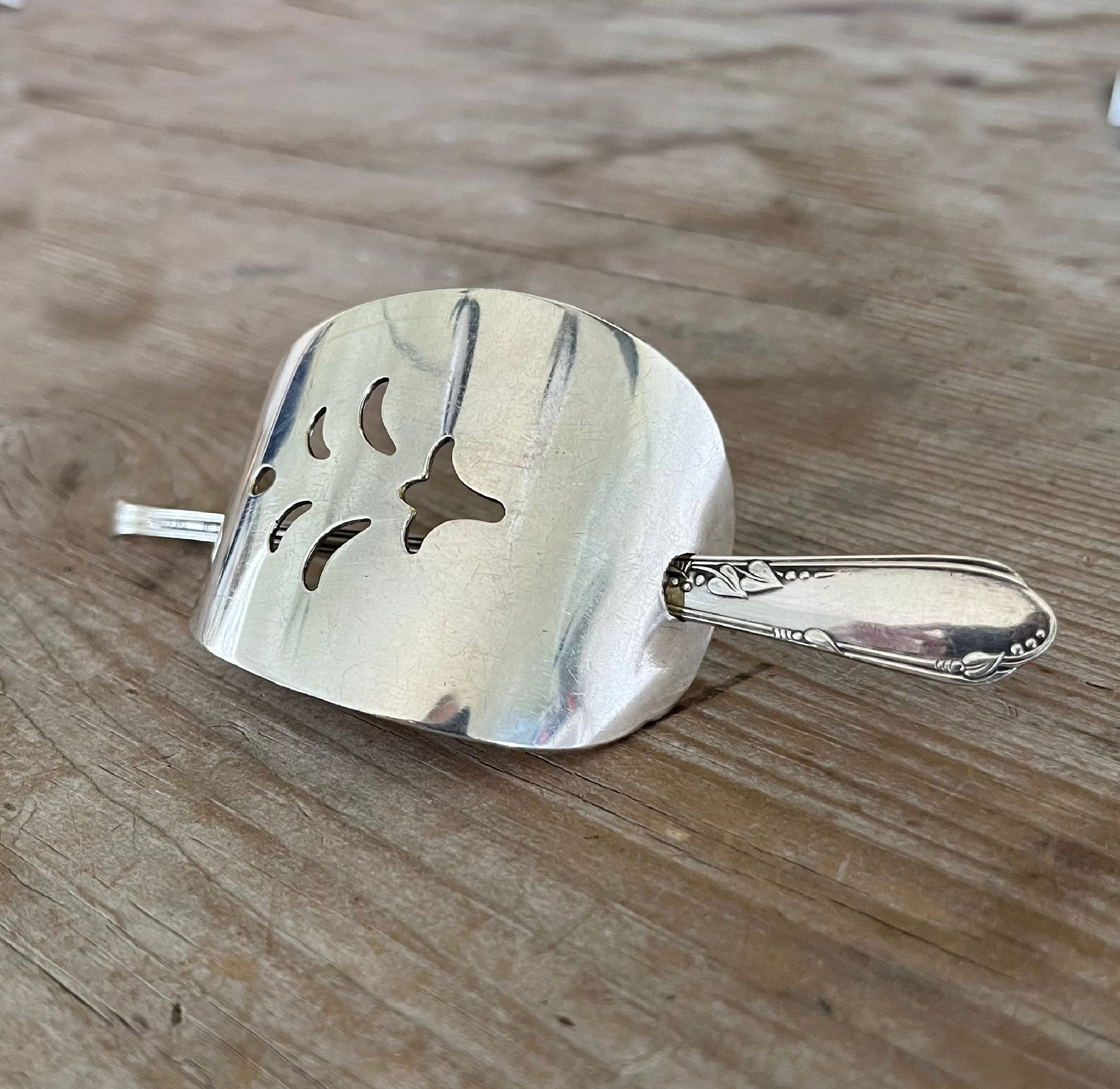 Close-up of vintage cake server barrette showing elegant pierced cutouts and spoon stick detail