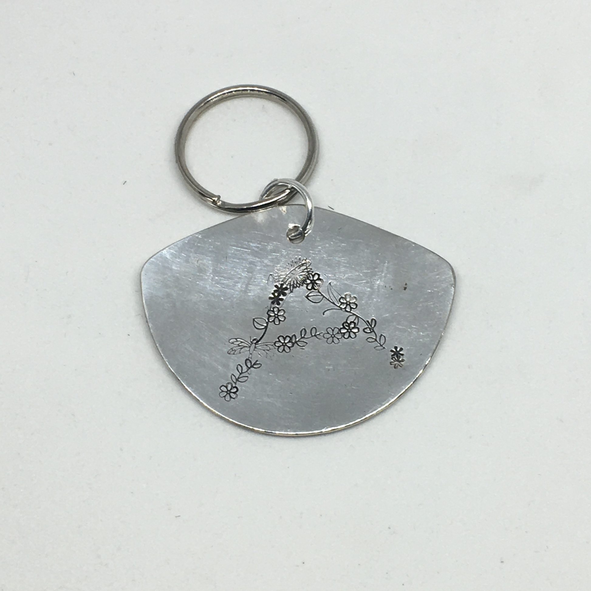 Close-up of floral monogram A hand-stamped on vintage spoon keychain showing spring flower detail