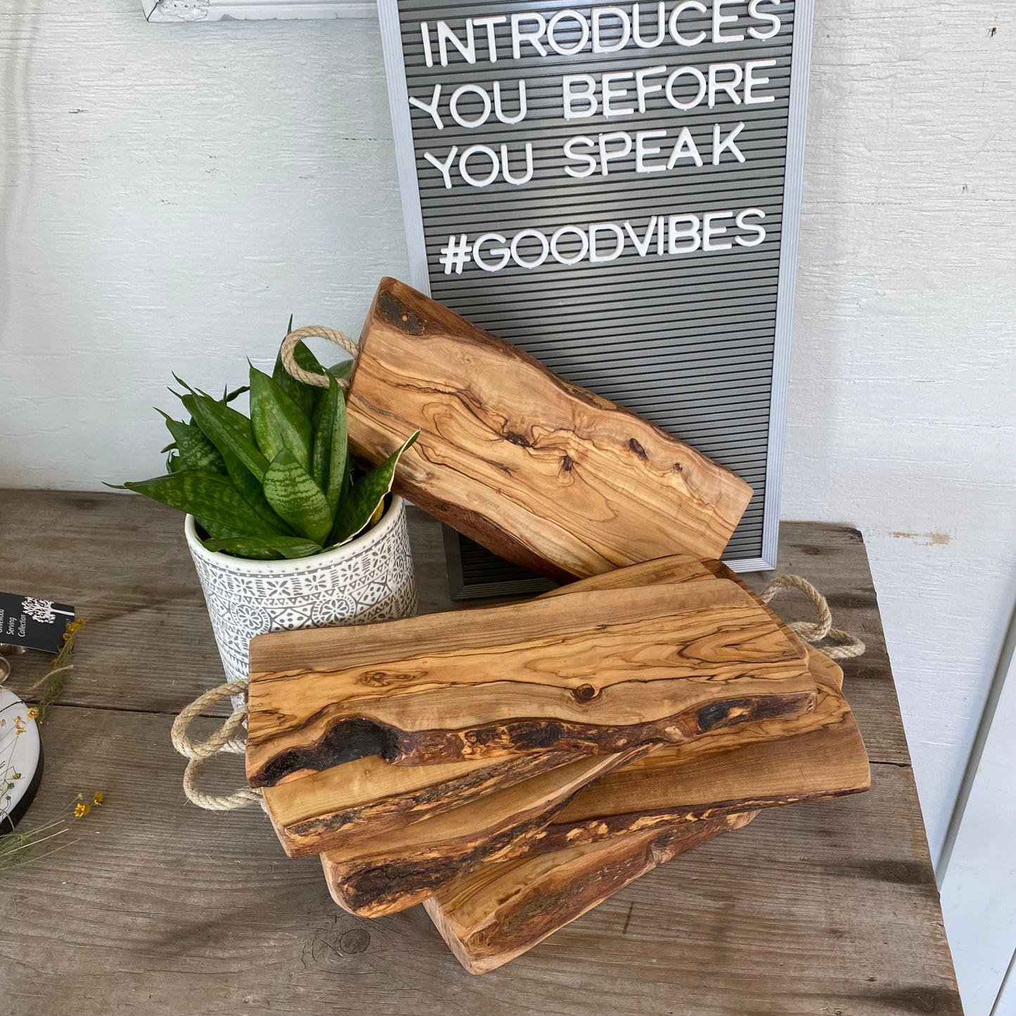 Stack of Italian olivewood charcuterie boards with rustic bark edges and rope handles - handcrafted from 150-year-old wood